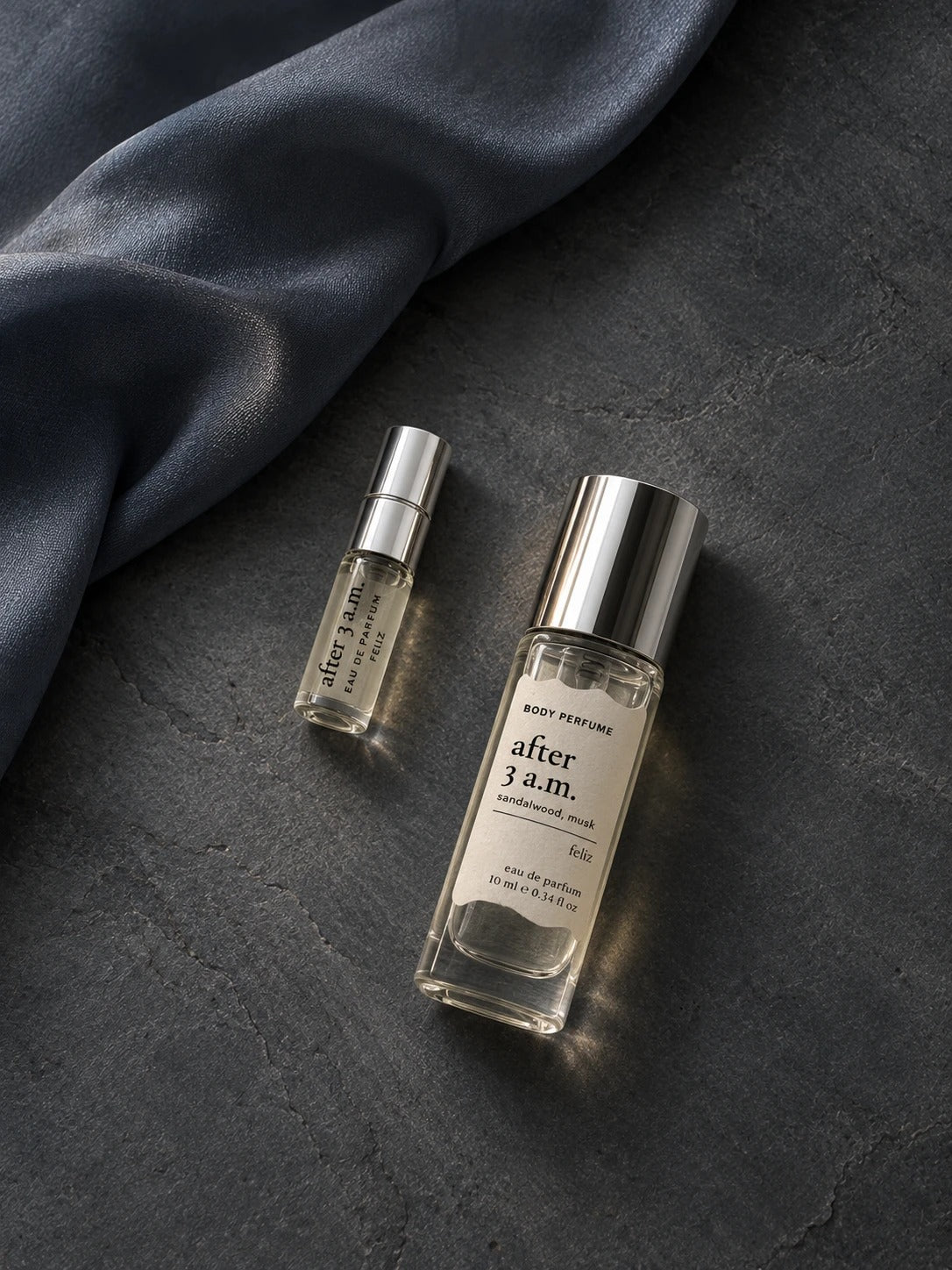 03 after 3 a.m. 10ml and 2ml perfume bottles together on dark stone