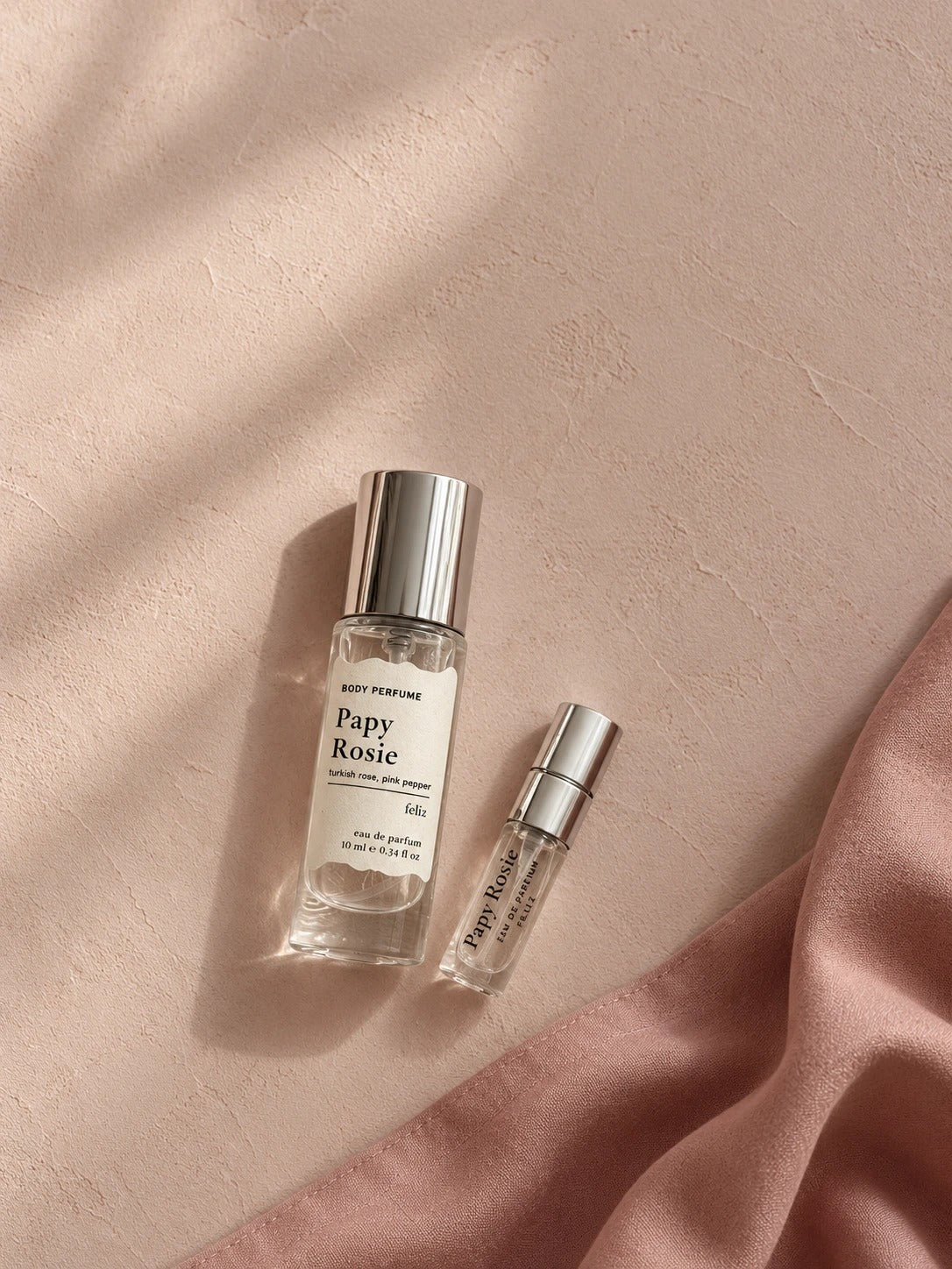 02 Papy ~ Rosie 10ml and 2ml perfume bottles together on a pink surface