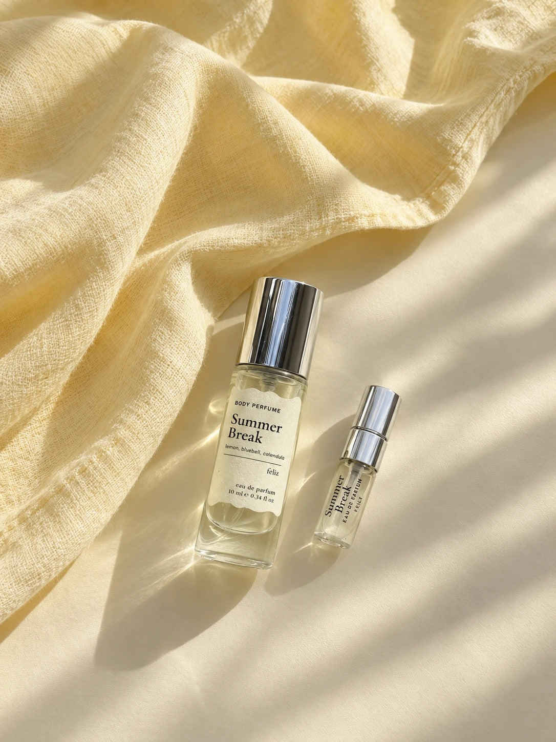 04 Summer Break 10ml and 2ml perfume bottles together on pale yellow cloth