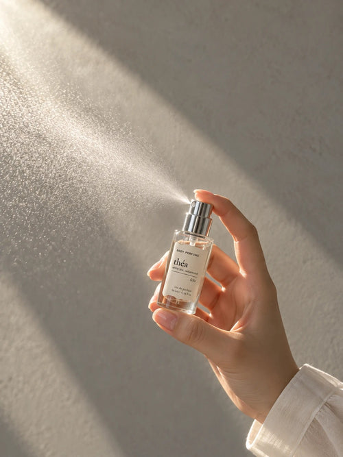 01 théa 10ml body perfume being sprayed, with fine mist visible