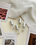 Four 2ml Feliz perfume vials, Papy Rosie, after 3 a.m., Summer Break and théa, with their scent cards on cream linen