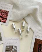 Four 2ml Feliz perfume vials, Papy Rosie, after 3 a.m., Summer Break and théa, with their scent cards on cream linen